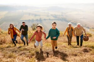Playful extended family running up the hill in autumn day.