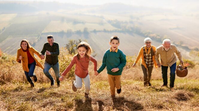 Playful extended family running up the hill in autumn day.